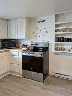 a kitchen with stainless steel appliances a stove and white cabinets