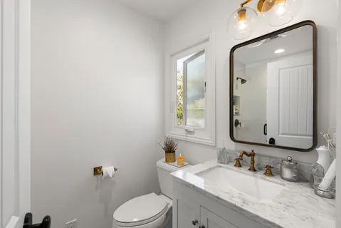 a bathroom with a granite countertop toilet sink and mirror