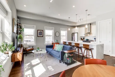a living room with furniture kitchen view and a large window