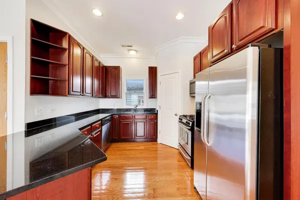 a kitchen with stainless steel appliances granite countertop a refrigerator a stove and a sink with wooden floor