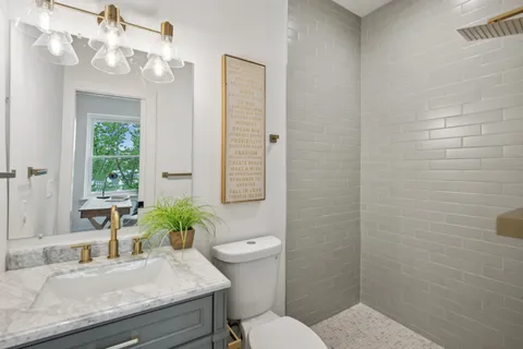 a bathroom with a granite countertop sink a toilet and shower