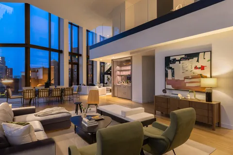 a living room with couches bookshelf and a stove with wooden floor