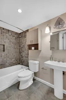 a bathroom with a toilet a sink a mirror a bathtub and shower