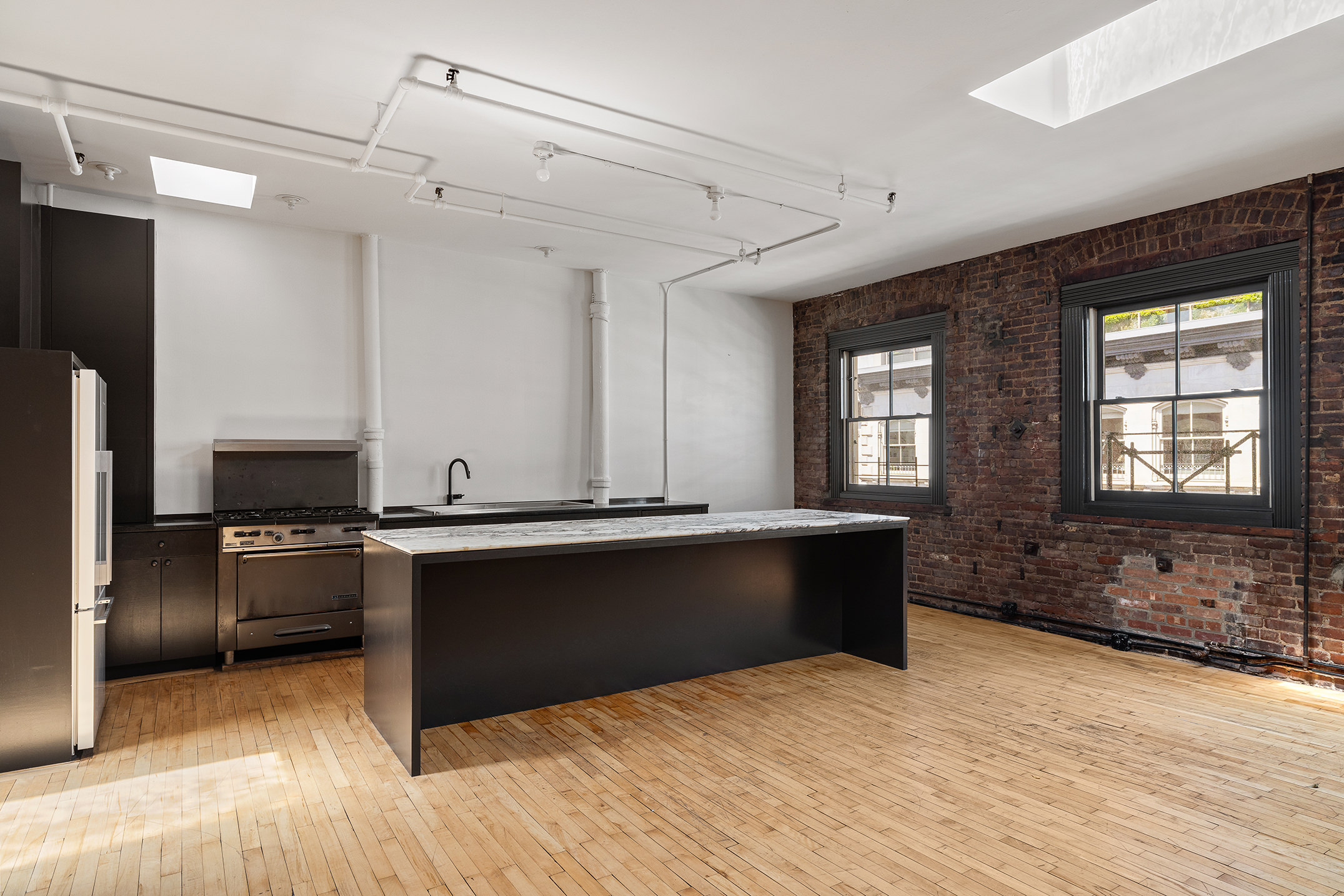 47 Howard Street, Unit 5 Manhattan, NY 10013 - Photo 3 of 9 a kitchen with stainless steel appliances granite countertop a sink and a refrigerator