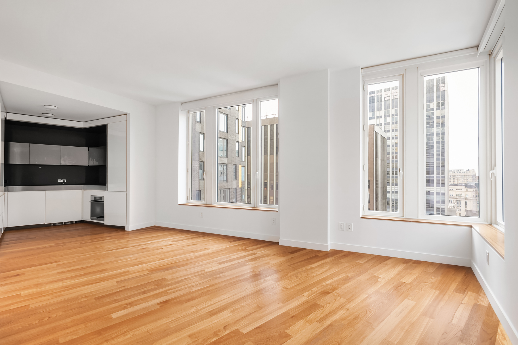a view of an empty room with a window and wooden floor