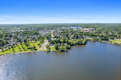 an aerial view of a houses with a yard and lake view in back
