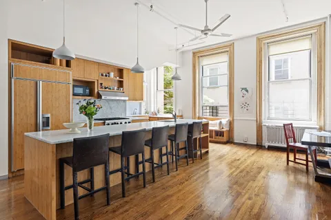 a kitchen with stainless steel appliances granite countertop a stove a refrigerator a kitchen island a dining table and chairs with wooden floor