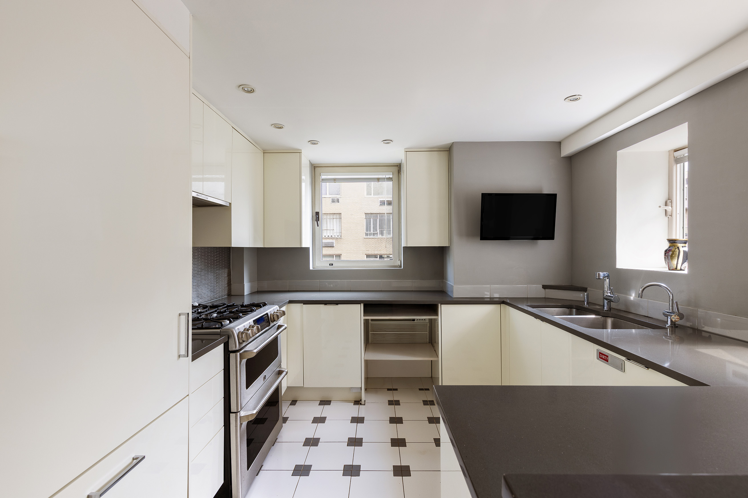 860 5th Avenue, Unit 11E Manhattan, NY 10065 - Photo 5 of 9 a kitchen with a sink a stove a microwave and cabinets