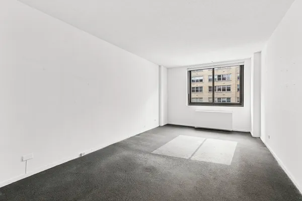 an empty room with windows and refrigerator