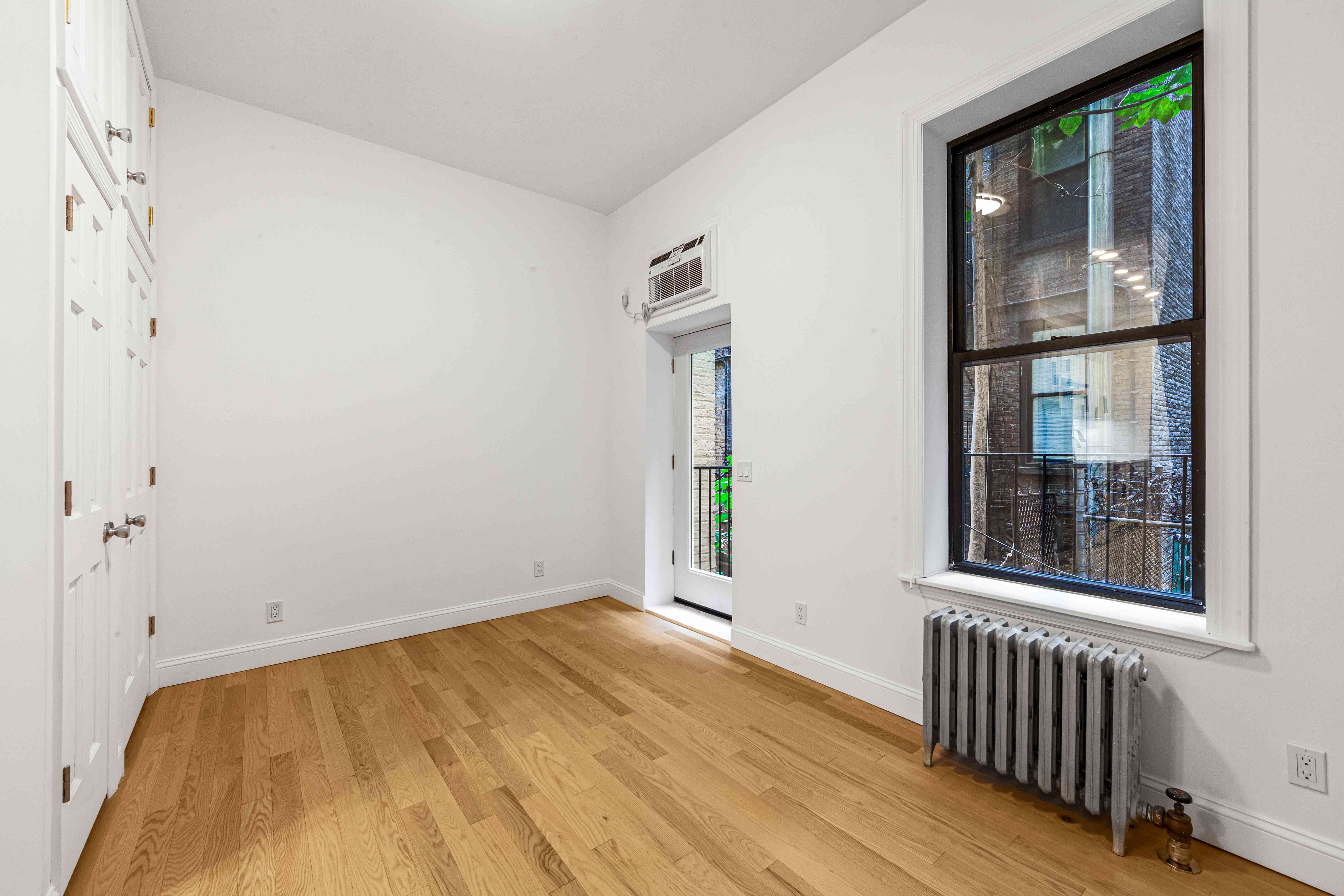 304 East 11th Street, Unit 1C Manhattan, NY 10003 - Photo 7 of 16 a view of an empty room with wooden floor and a window