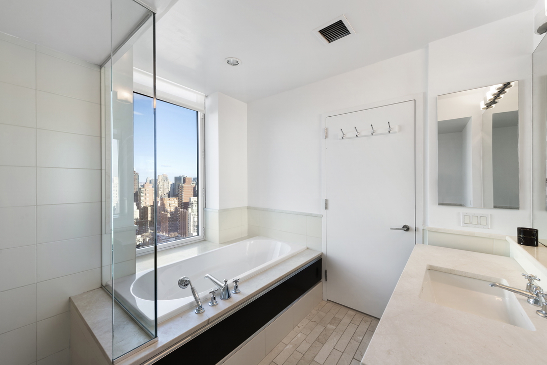 207 East 57th Street, Unit 34A Manhattan, NY 10022 - Photo 11 of 22 a bathroom with a tub and a view of living room