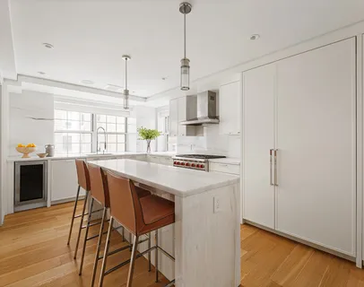 a kitchen with stainless steel appliances a white table chairs and a wooden floor