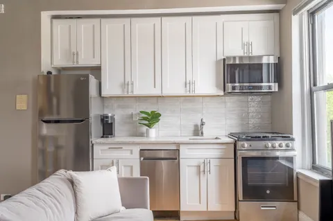 a kitchen with stainless steel appliances granite countertop a refrigerator sink stove and white cabinets