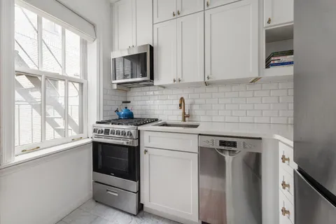 a kitchen with stainless steel appliances white cabinets and a stove top oven