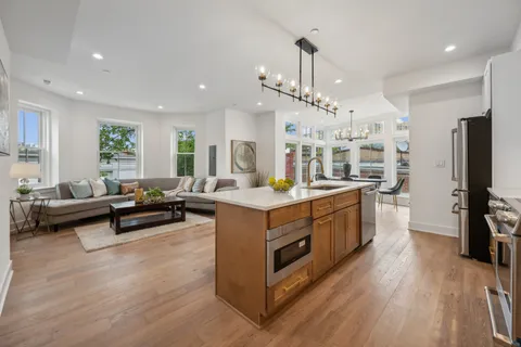 a large kitchen with stainless steel appliances a stove a sink dishwasher and a dining table with wooden floor