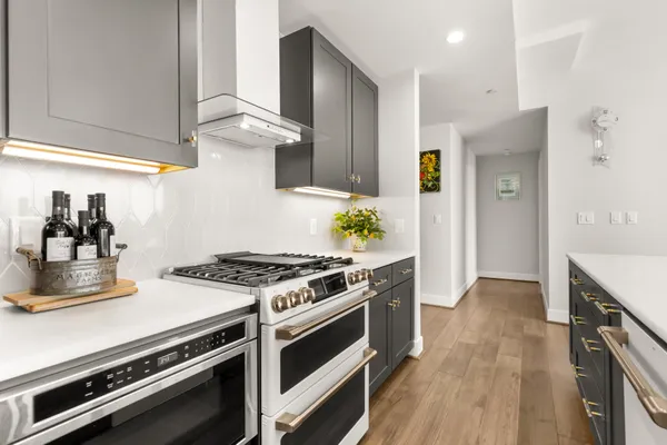 a kitchen with stainless steel appliances a stove and white cabinets with wooden floor