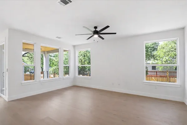 an empty room with windows and chandelier fan