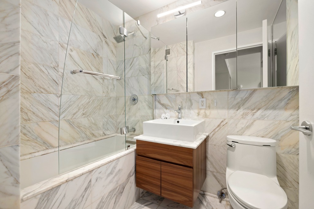 350 West 42nd Street, Unit 23D Manhattan, NY 10036 - Photo 8 of 15 a bathroom with a sink toilet and shower