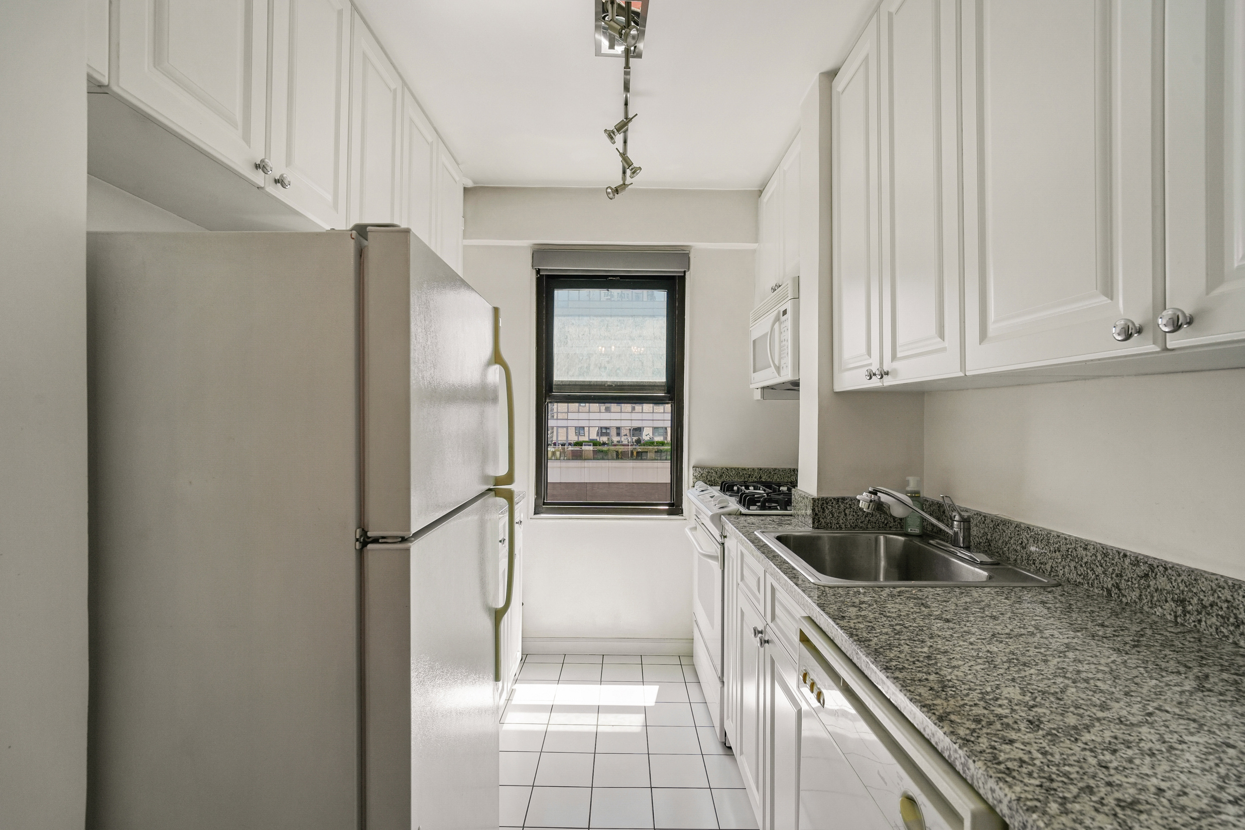 240 East 76th Street, Unit 10L Manhattan, NY 10021 - Photo 4 of 9 a kitchen with a refrigerator a sink and cabinets