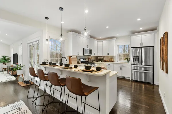 a kitchen with stainless steel appliances granite countertop a sink a stove a refrigerator and island with wooden floor