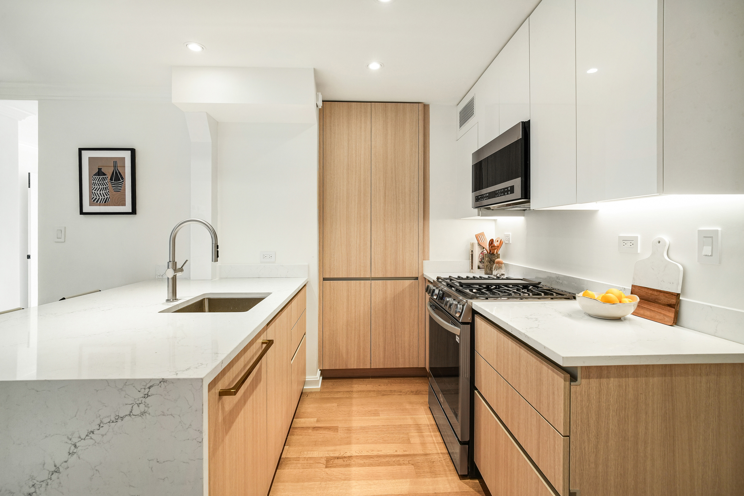 31 Jane Street, Unit 10FG Manhattan, NY 10014 - Photo 11 of 27 a kitchen with stainless steel appliances granite countertop a sink stove and microwave