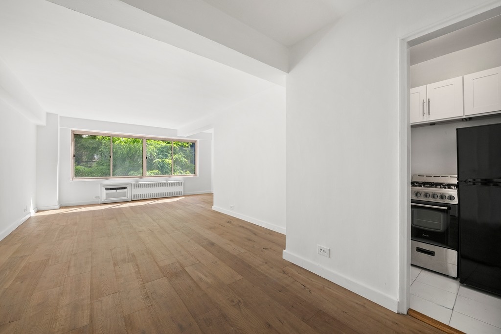 225 East 46th Street, Unit 2G Manhattan, NY 10017 - Photo 1 of 6 a view of an empty room with a window and wooden floor