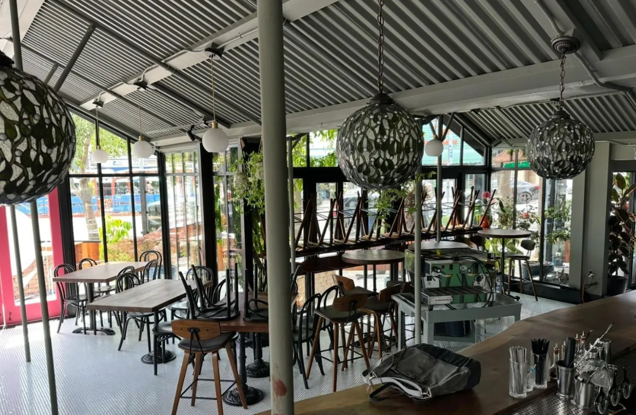 a view of a patio with table and chairs potted plants and floor to ceiling window