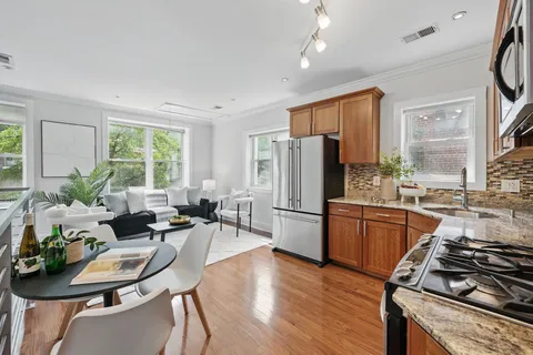 a kitchen with stainless steel appliances a stove a refrigerator a sink a dining table and chairs with wooden floor
