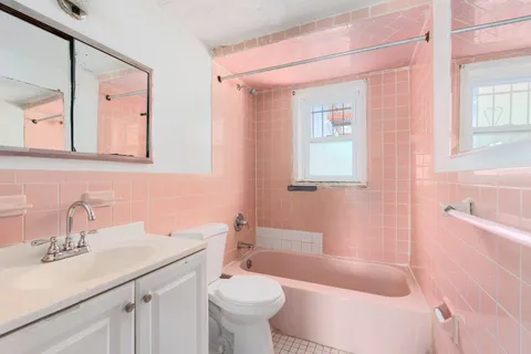 a bathroom with a sink a toilet a mirror a vanity a bathtub and shower
