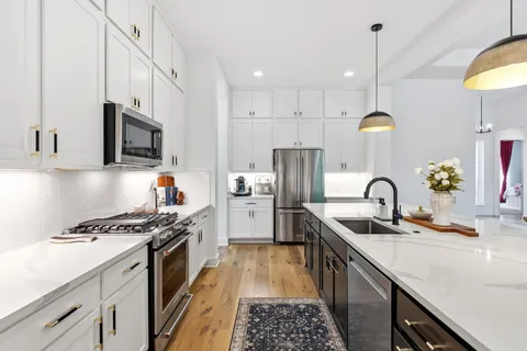 a kitchen with stainless steel appliances a sink a stove a refrigerator and cabinets