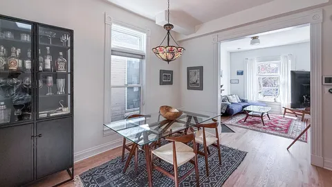 a dining room with wooden floor a chandelier a wooden table and chairs