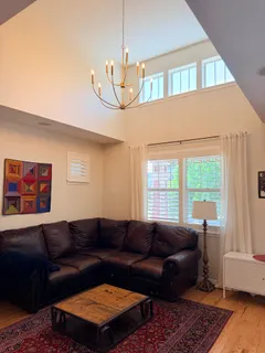 a living room with furniture a large window and a chandelier