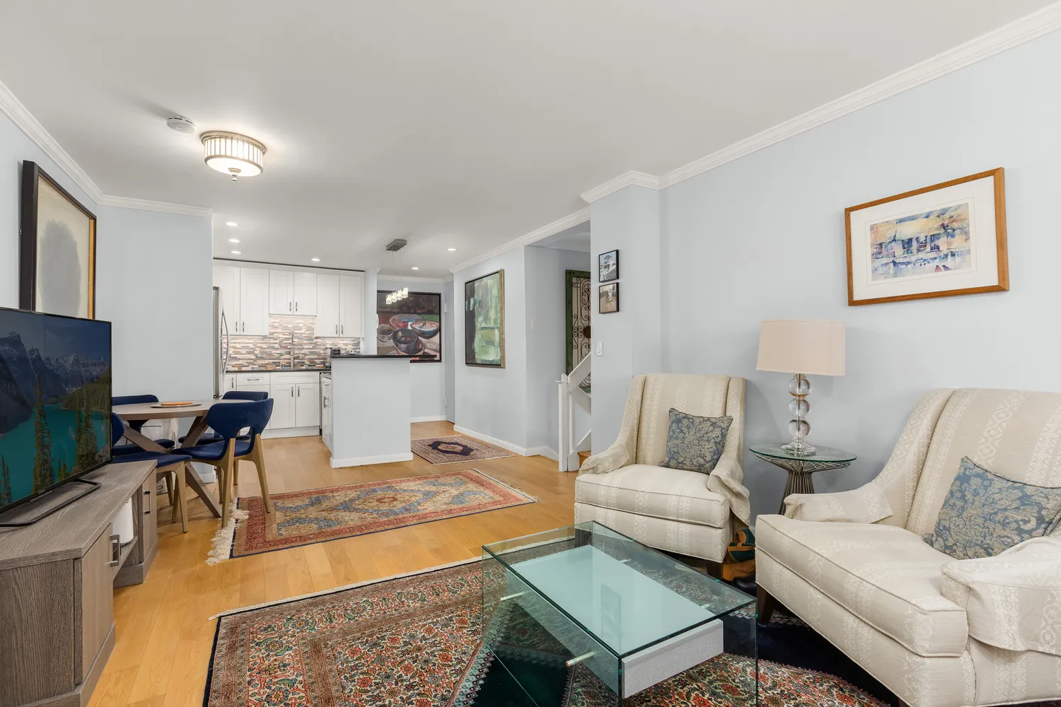 a living room with furniture a flat screen tv and kitchen view