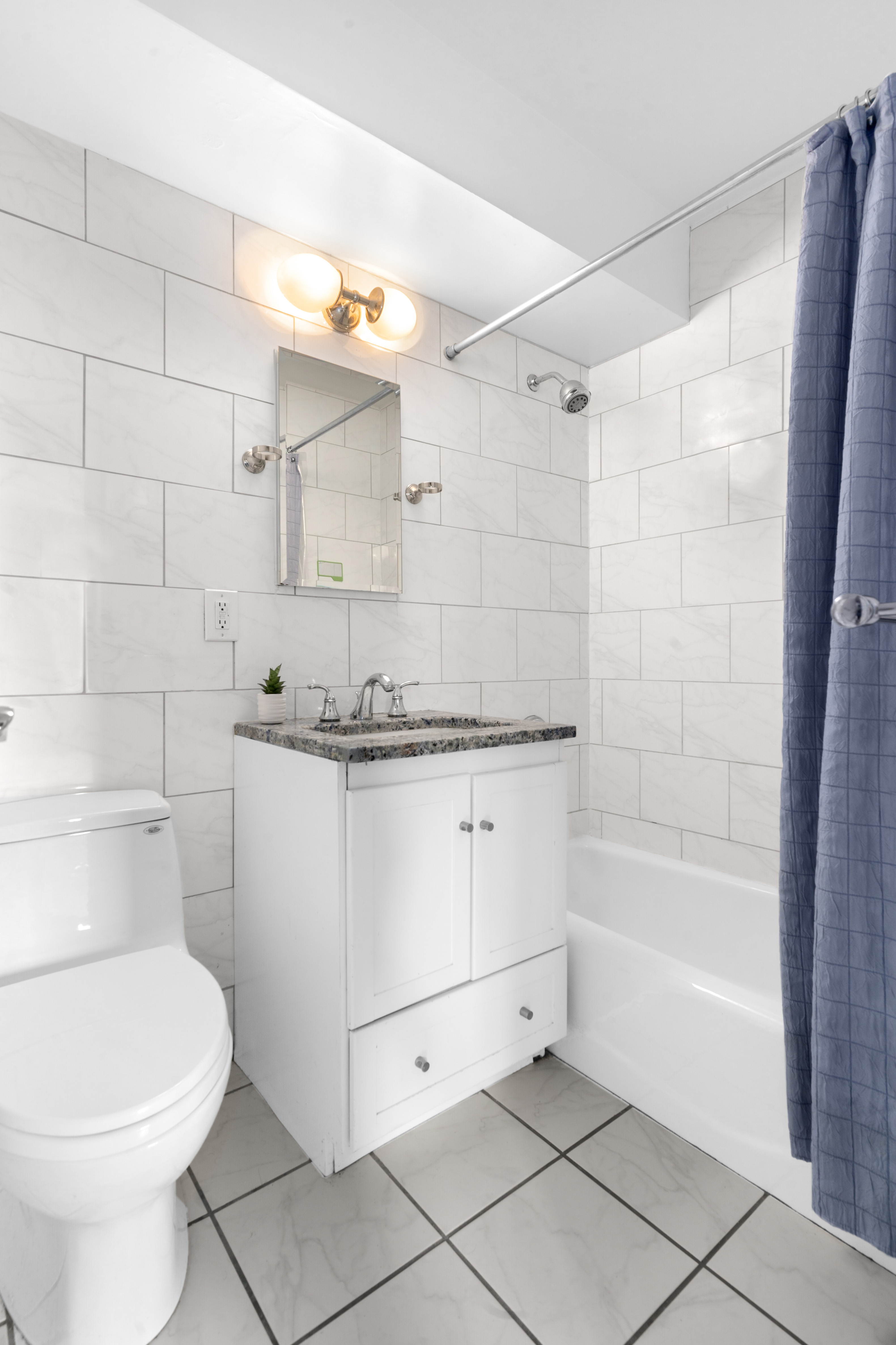 303 West 66th Street, Unit 18EE Manhattan, NY 10023 - Photo 17 of 24 a bathroom with a granite countertop sink a toilet and bathtub