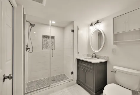 a bathroom with a granite countertop sink toilet mirror and shower