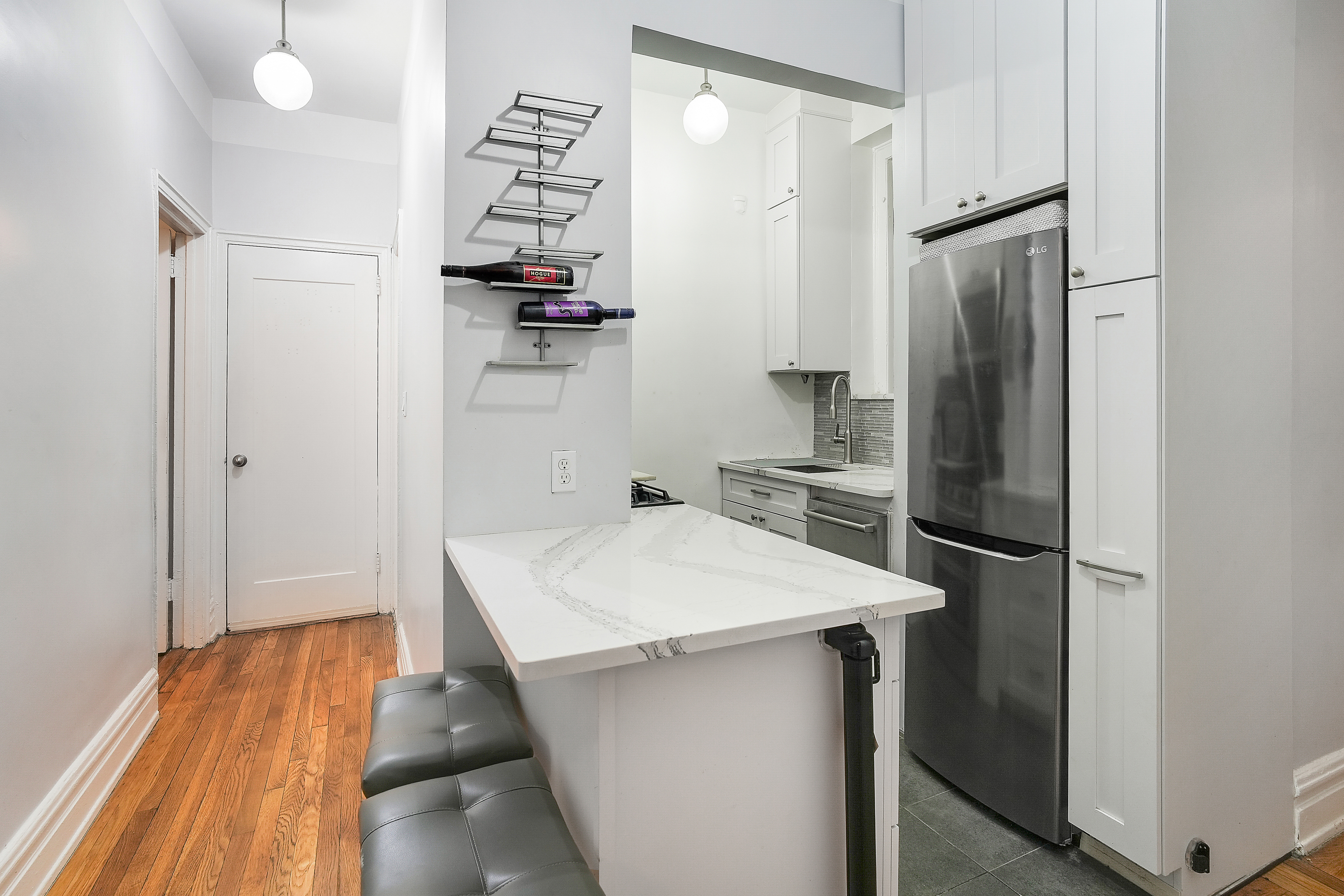 205 West 54th Street, Unit 3A Manhattan, NY 10019 - Photo 7 of 14 a kitchen with stainless steel appliances a refrigerator and a wooden floor