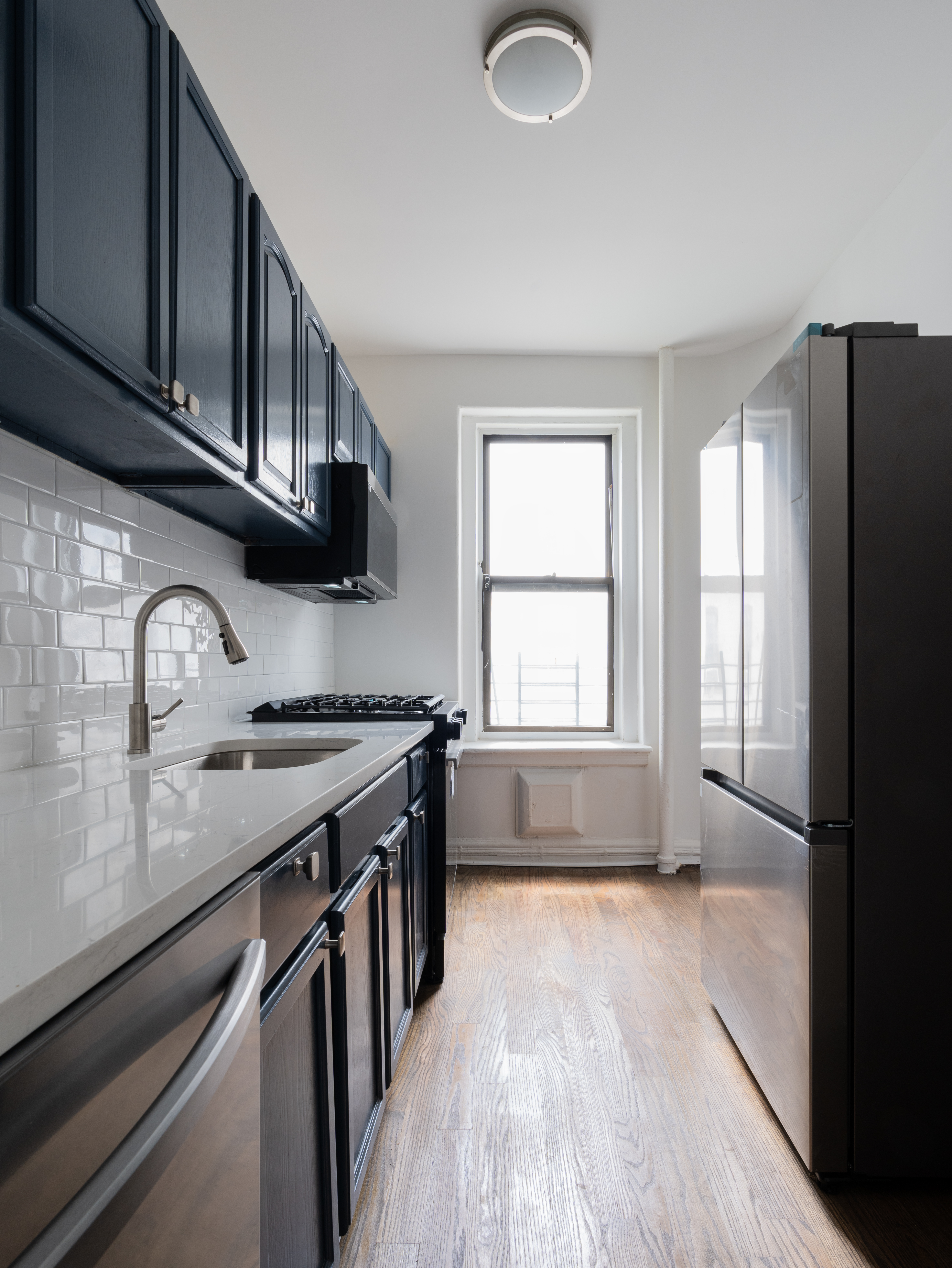 1405 Prospect Place, Unit B11 Brooklyn, NY 11213 - Photo 4 of 12 a kitchen with granite countertop a stove a sink dishwasher and a refrigerator with wooden floor