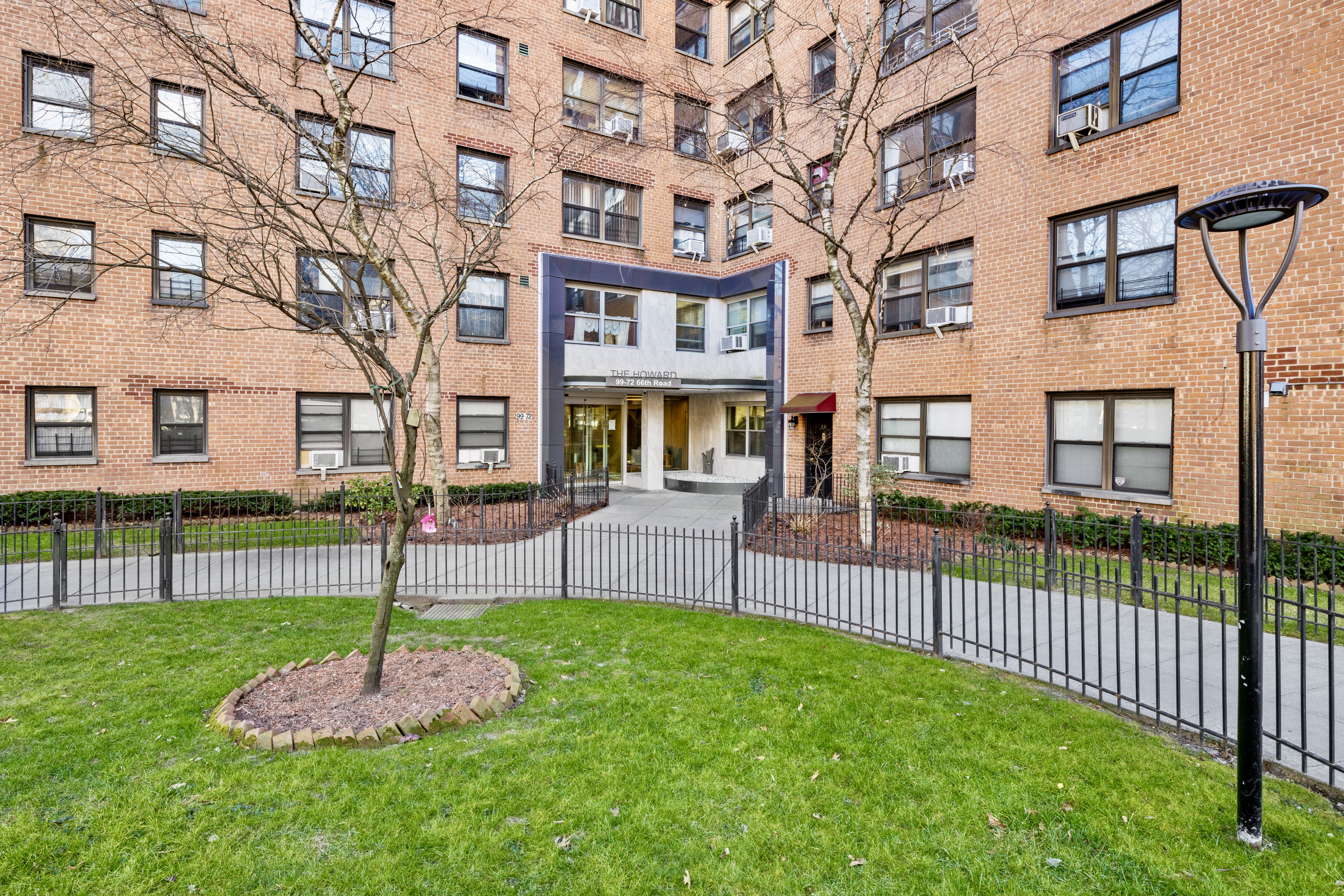 99-72 66th Road, Unit 3R Queens, NY 11374 - Photo 9 of 10 a front view of a brick building with a yard