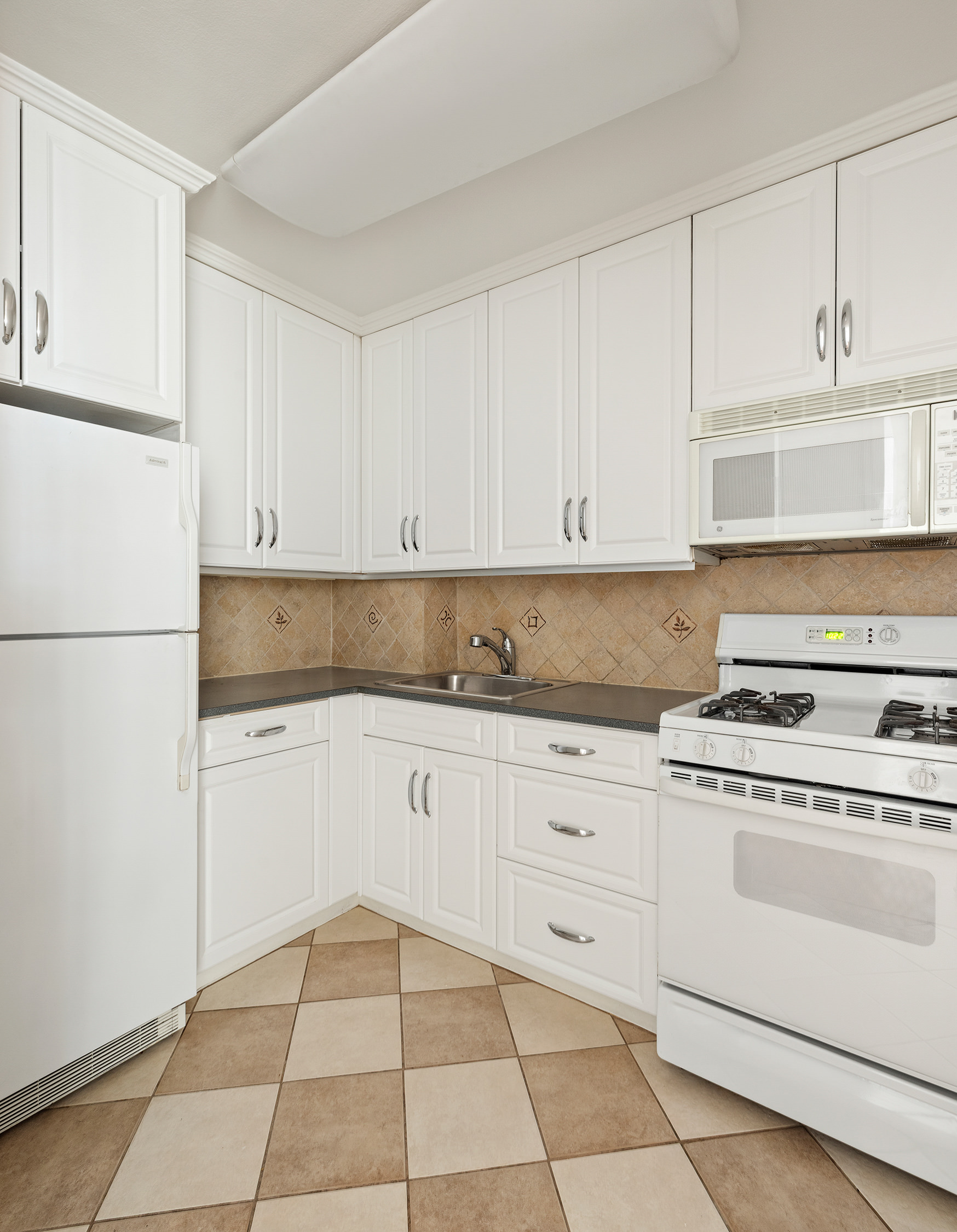 55 East 87th Street, Unit 9M Manhattan, NY 10128 - Photo 8 of 11 a kitchen with cabinets appliances and a sink