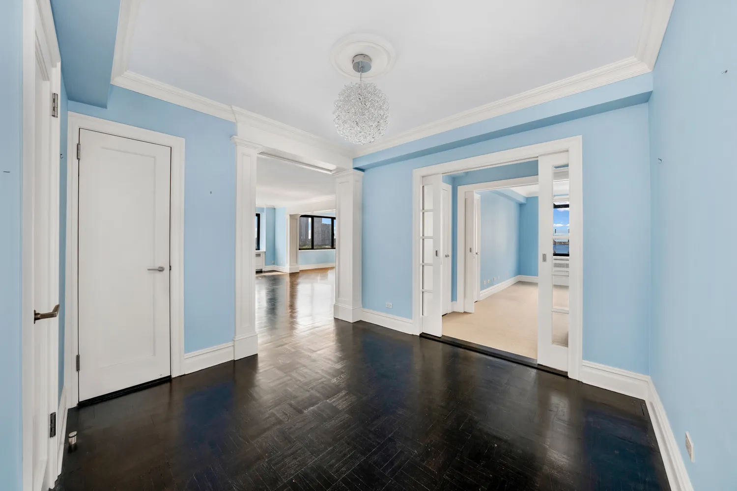 a view of a hallway with wooden floor and a bathroom