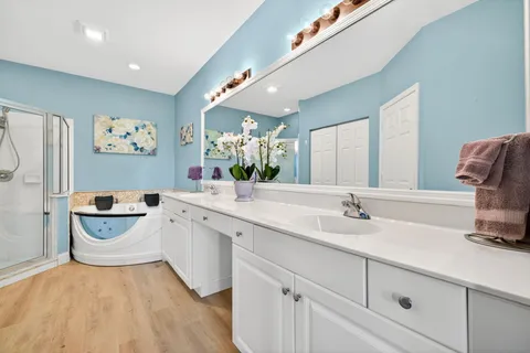 a spacious bathroom with a double vanity sink a mirror a bathtub and next to a window