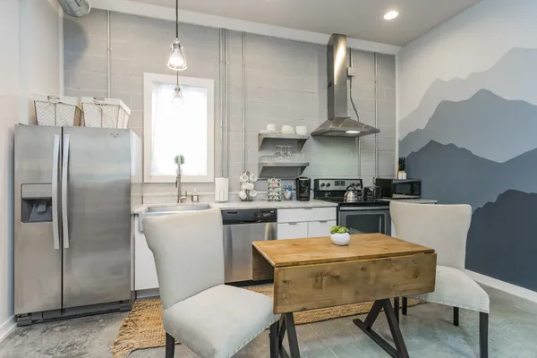 a kitchen with stainless steel appliances a dining table chairs and refrigerator