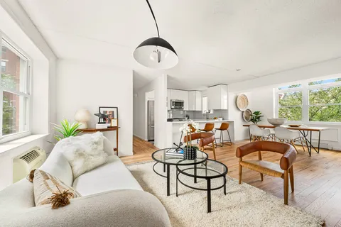 a living room with furniture kitchen view and a large window