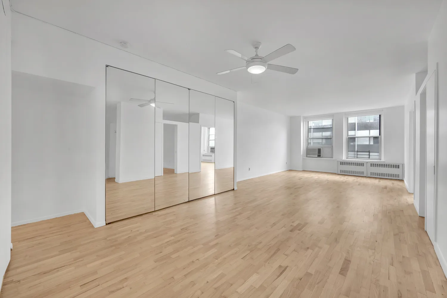 a view of empty room with wooden floor and fan