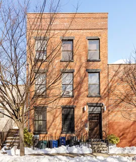 a front view of a building with large trees