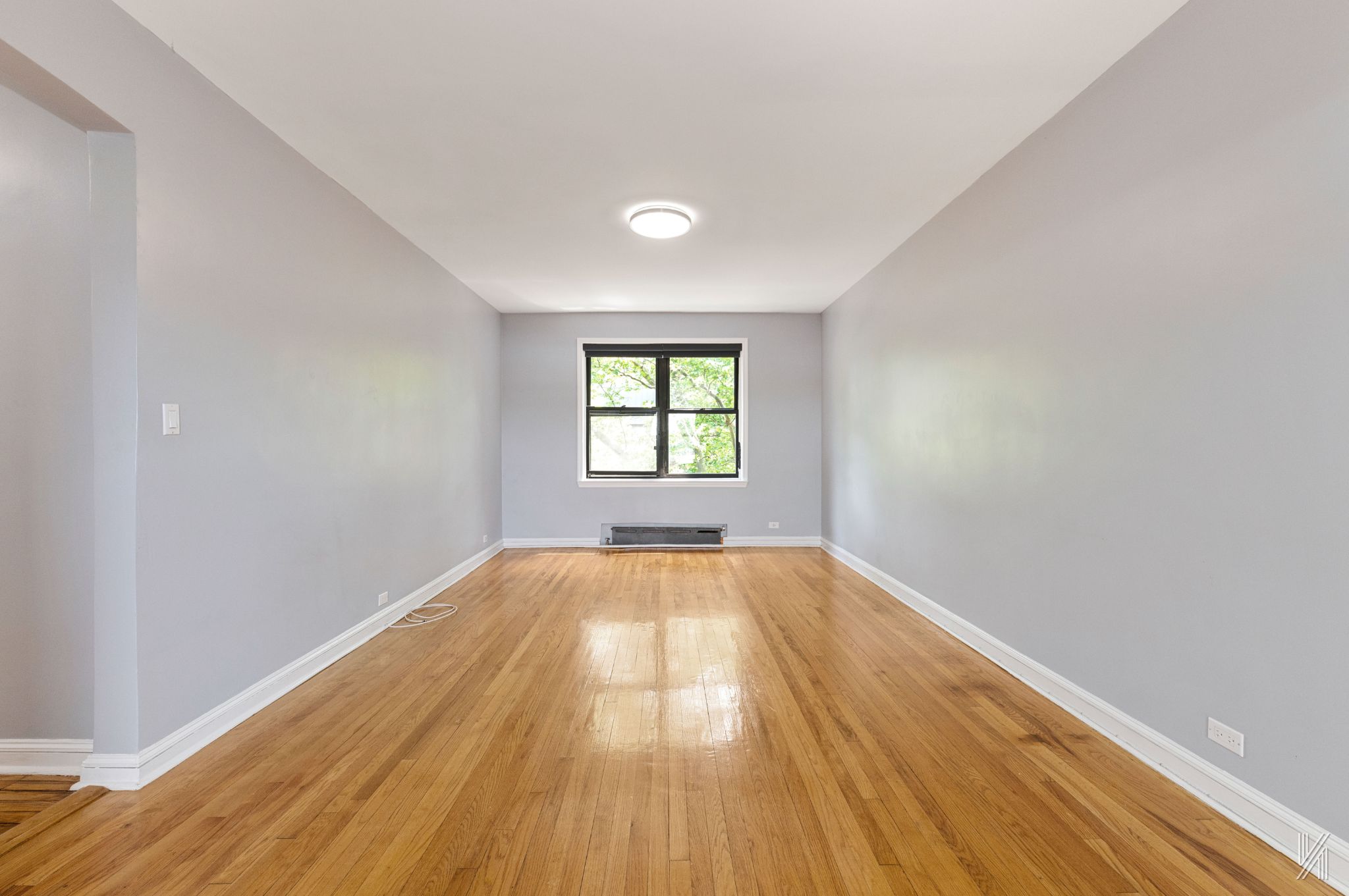 22-20 76th Street, Unit C3 Queens, NY 11370 - Photo 5 of 20 wooden floor in an empty room with a window