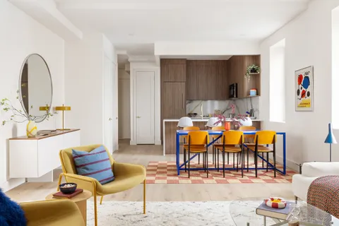 a living room with furniture kitchen view and a wooden floor
