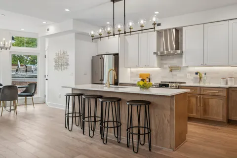 a kitchen with stainless steel appliances granite countertop a refrigerator a sink dishwasher a stove and white cabinets with wooden floor