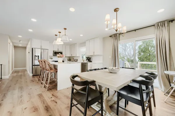 a view of a dining room and livingroom with furniture wooden floor a chandelier