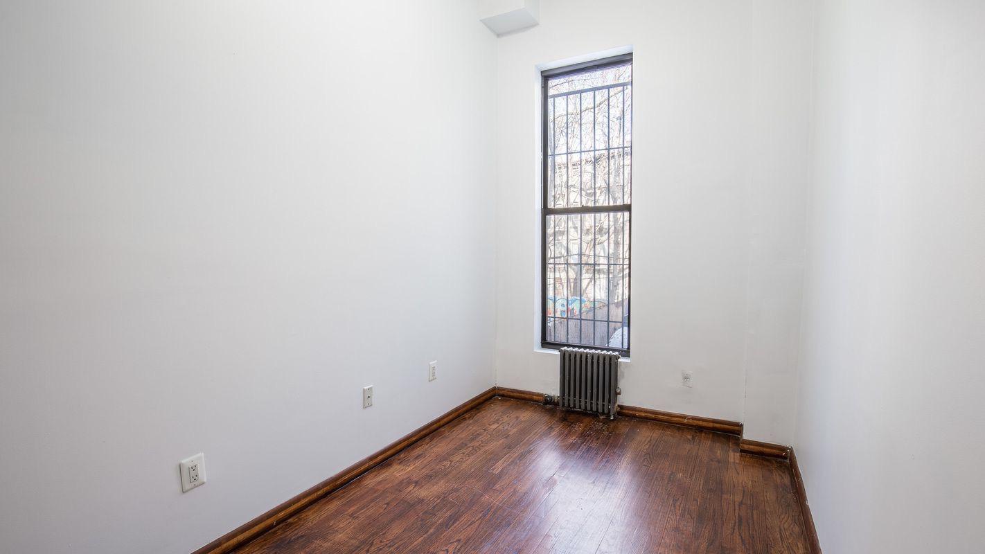 27 Brevoort Place, Unit 2 Brooklyn, NY 11216 - Photo 6 of 9 an empty room with wooden floor and windows